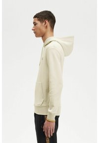 Sudadera de color beige claro con bolsillo canguro, capucha ajustable, puños y bajo acanalados, que presenta un sutil detalle de marca en el pecho.