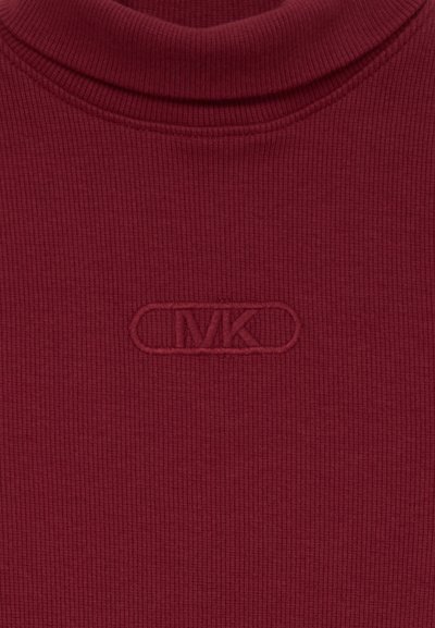 Bordo ribota augstā apkakle, kas adornēta ar izteiksmīgu izšūtu "MK" logotipu ovālā uzlīmē. Tekstūra ir mīksta un pieguļoša.