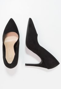 Svarta mocka högklackade skor med spetsig tå och urklippt design. Har en slät, ljus inläggssula och en elegant, avsmalnande klack.