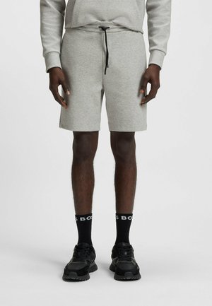 Shorts in cotone grigio con vita elasticizzata e cordino nero. Abbinati a sneakers nere e calze con scritte bianche.