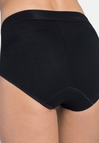 Culotte en coton noir avec une texture lisse, taille haute et bords festonnés. Présente un design ajusté et des détails de couture minimaux.
