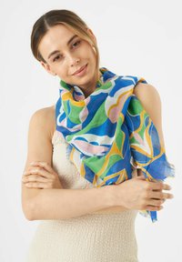 Écharpe légère et colorée dotée de motifs floraux bleus, verts, roses et jaunes, avec des bords frangés et une texture douce et transparente.