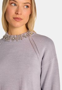 Maglione lilla con dettagli di perline sul collo, con scollo a girocollo, accenti a costine e design a maglia aperta sulle spalle.