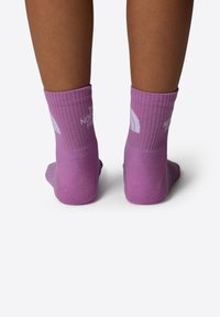 Calcetines morados con textura acanalada y un logo blanco en la parte posterior. De longitud hasta el tobillo con un acabado suave, ideales para un uso casual.