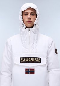 Biała, lekka kurtka z wysokim kołnierzem, zapięciem na zamek i kieszenią z przodu. Posiada naszywkę z logo oraz akcent w postaci flagi Norwegii.