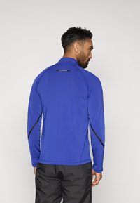 Dug rukava atletska majica u vibrantnoj plavoj boji s visokim ovratnikom, s crnim detaljima uz rukave i logotipom na gornjem dijelu leđa.