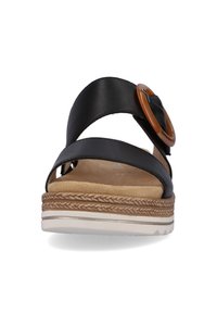 Black leather sandal with two crossed straps, featuring a round brown buckle. Cork footbed and textured, layered sole with white accents.