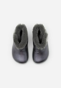 Bottes de cheville en fourrure grise avec une finition métallique, présentant une surface lisse et une semelle blanche contrastante. Aucun matériel ou motif visible.