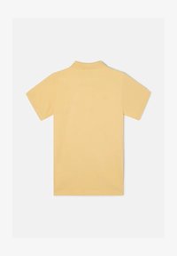 Polo de manga corta en suave y liso tejido amarillo. Presenta un cuello clásico y un ajuste entallado sin marcas ni patrones visibles.
