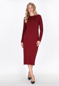Bordeauxfarbenes langärmeliges Kleid mit rundem Ausschnitt, knielangem Design und Knopfakzenten an den Ärmeln, gefertigt aus einem weichen, strukturierten Stoff.