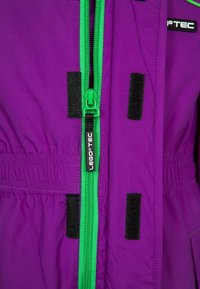 Fioletowa, wodoodporna kurtka z zielonym zamkiem z przodu, czarnymi akcentami na rzepy i elastycznym pasem. Posiada logo LEGO TEC na klatce piersiowej.
