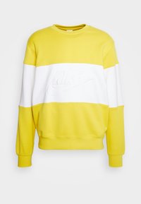 Gul och vit sweatshirt i bomull, med rund halsringning, långa ärmar och en präglad Nike-logotyp över bröstet.