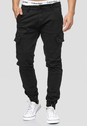 Black cargo pants with elastic cuffs, featuring side pockets and a Calvin Klein logo waistband, made from durable, smooth fabric.