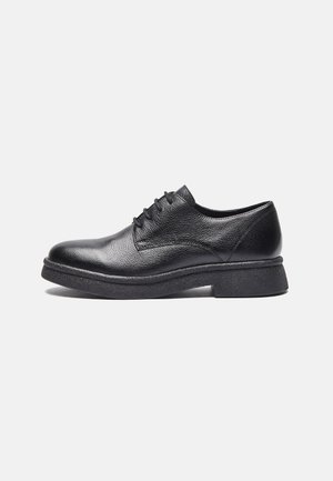 Chaussure de ville pour homme en cuir noir à lacets, tige texturée et semelle en caoutchouc épaisse, présentée en profil droit sur fond blanc.