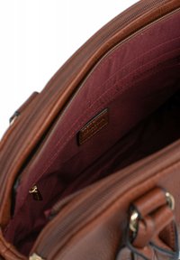 Borsa in pelle marrone con una fodera in tessuto bordeaux e tasche interne, dotata di chiusura con zip e un piccolo tassello in pelle con marchio.