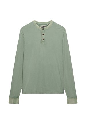 Jasnozielona koszula Henley z długim rękawem, trzema brązowymi guzikami oraz kontrastowym przeszyciem na mankietach i kołnierzyku, rozłożona na płasko na białym tle.