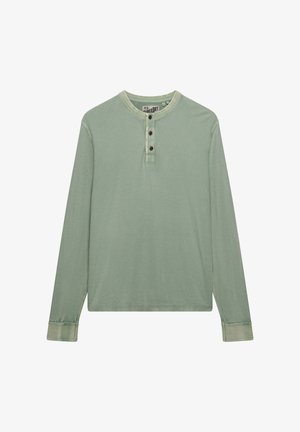 Jasnozielona koszula Henley z długim rękawem, trzema brązowymi guzikami oraz kontrastowym przeszyciem na mankietach i kołnierzyku, rozłożona na płasko na białym tle.