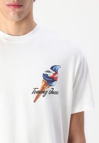 Hvid bomulds t-shirt med et farverigt isvaffel-grafik og "Tommy Jeans" tekst trykt på venstre brystområde.