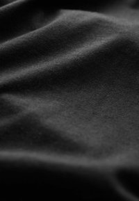 Fekete textil sima felülettel, finom fodrokkal és ráncokkal. Az anyag könnyűnek és nem fénylőnek tűnik.