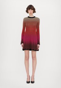 Vestido de manga longa com um padrão em chevron em tons degradê de bege, laranja, rosa e preto. Feito de um tecido liso e elástico.