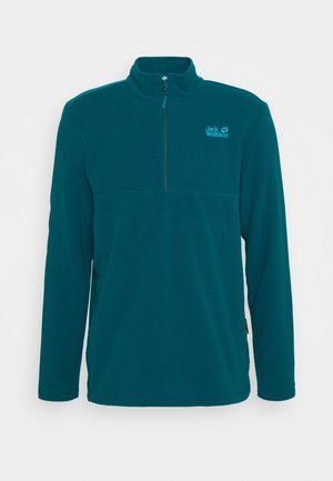 Pull polaire à manches longues de couleur sarcelle avec une fermeture éclair à moitié et un logo Jack Wolfskin sur la poitrine, sur un fond uni.