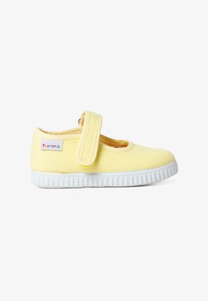 Zapato de lona amarillo con una tira de Velcro, puntera redonda y suela de goma blanca texturizada. Presenta una etiqueta de logo en el lateral.
