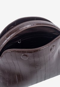 Geantă maro din piele cu model croco texturat. Dispune de un buzunar cu fermoar în interior și două nasturi rotunzi cu capse în exterior.