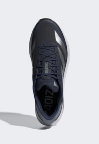 Námorné športové topánky s textúrovaným zvrškom, sivými akcentmi, reflexnými pruhmi a odpruženou podrážkou. Obsahujú ploché šnúrky a polstrovaný jazyk.