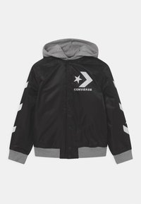 Giacca con cappuccio nera e grigia caratterizzata da una finitura in satin lucido, bottoni a pressione e grafiche di una stella e una freccia sul davanti e sulle maniche.