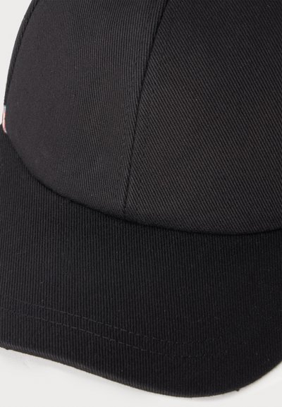 Gros plan sur une casquette de baseball en tissu noir montrant la visière incurvée et les panneaux cousus.