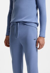 Lichtblauw getextureerd thermisch shirt en broek met een nauwsluitend ontwerp, trekkoord in de taille en een discreet "BOSS"-logo op de broek.