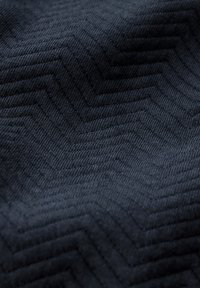 Tessuto di un blu navy scuro con una texture a zigzag, caratterizzato da una finitura morbida e da linee in rilievo che creano un dettaglio di superficie sofisticato.