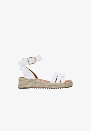 Sandalias espadrilles blancas con suela de yute trenzada, tira para el tobillo con hebilla y un diseño cruzado con detalle de nudo decorativo.