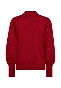 Röd pullovertröja med puffärmar, prydd med silvernitar längs ärmarna. Ribbad krage och mudd, stickad struktur över hela tröjan.