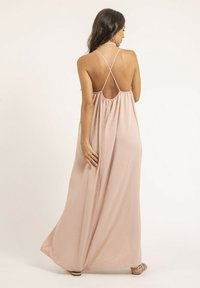 Vue arrière d'une robe maxi fluide, rose clair, avec une taille froncée, des bretelles en croix et une texture de tissu lisse et léger.