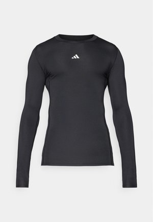 Black long-sleeve athletic shirt made of smooth, stretchy material. Features a round neckline and subtle white logo on the chest.