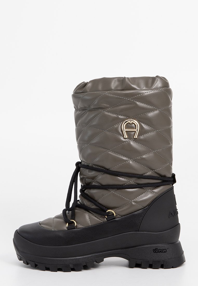 Gepolsterter, dunkelgrauer Winterstiefel mit schwarzer Gummisohle, schwarzen Schnürsenkeln, die um den Knöchel gewickelt sind, und goldenem Metallic-Logo auf der Oberseite.