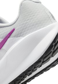 Baskets blanches de sport avec une tige en mesh texturé, des accents violets et une semelle en caoutchouc noir avec un motif de semelle pour une meilleure adhérence.