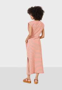 Gestreiftes Maxikleid in Orange und Creme, mit kurzen Ärmeln, seitlichem Schlitz und drapiertem Rückendesign, kombiniert mit braunen Riemchensandalen.