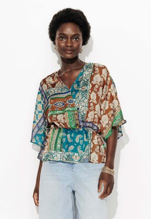 Haut à motifs marron et bleu canard avec un décolleté en V et des manches évasées. Présente des motifs floraux et de paisley, ainsi qu'une taille élastique avec un ourlet superposé.