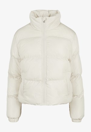 Szövetkabát, tiszta fehér színben, magas gallérral, cipzáras záródással és vízszintes párnázott kivitelezéssel, amely a szigetelésért felel.