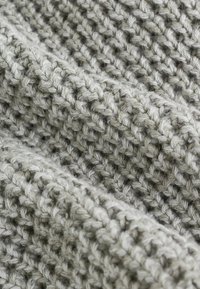 Tissu tricoté gris avec un motif texturé, composé de fil épais, offrant un aspect doux et confortable avec des points irréguliers.