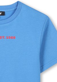 Camiseta de cuello redondo azul hecha de algodón; presenta el texto rojo "EST. 1989" impreso en el frente; textura suave, mangas cortas, corte estándar.