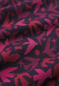 Gewebe mit dunklem Hintergrund und einem wiederholten Muster von Vögeln und abstrakten Formen in Pink- und Rottönen, das ein Textildesign zeigt.