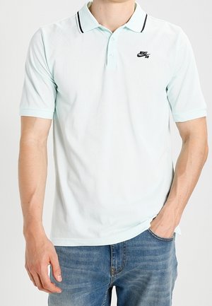 Polo vert menthe clair en tissu respirant, avec un logo Nike noir, des manches courtes et une patte de boutonnage à deux boutons avec des accents noirs.