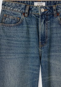 Jeans in denim blu con vestibilità regolare. Presentano cinque tasche, cuciture a contrasto, chiusura con bottoni metallici e un'etichetta sulla cintura.