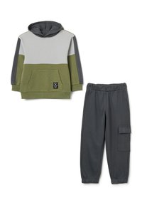 Felpa con cappuccio in verde oliva, grigio e grigio chiaro, con tasca anteriore; abbinata a pantaloni della tuta grigi scuri con tasca cargo laterale.