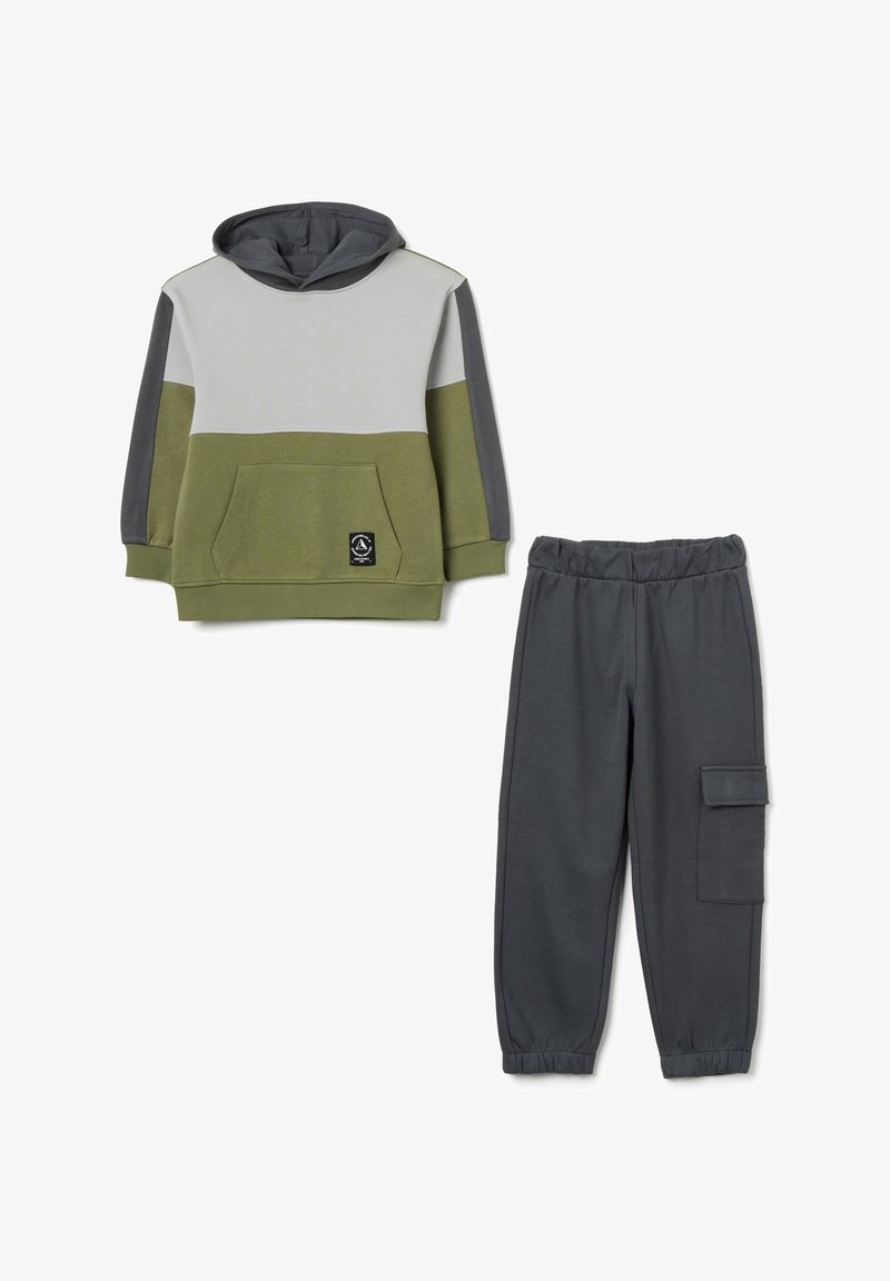 Felpa con cappuccio in verde oliva, grigio e grigio chiaro, con tasca anteriore; abbinata a pantaloni della tuta grigi scuri con tasca cargo laterale.