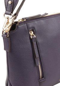 Sac à main en cuir violet avec une finition texturée, une quincaillerie en métal doré et une bandoulière amovible avec des accents polis.