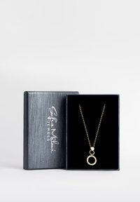 Goldene Halskette mit einem runden Anhänger, der mit klaren Steinen besetzt ist, präsentiert in einer mit schwarzem Samt ausgekleideten Schmuckschatulle mit einer strukturierten grauen Außenseite.